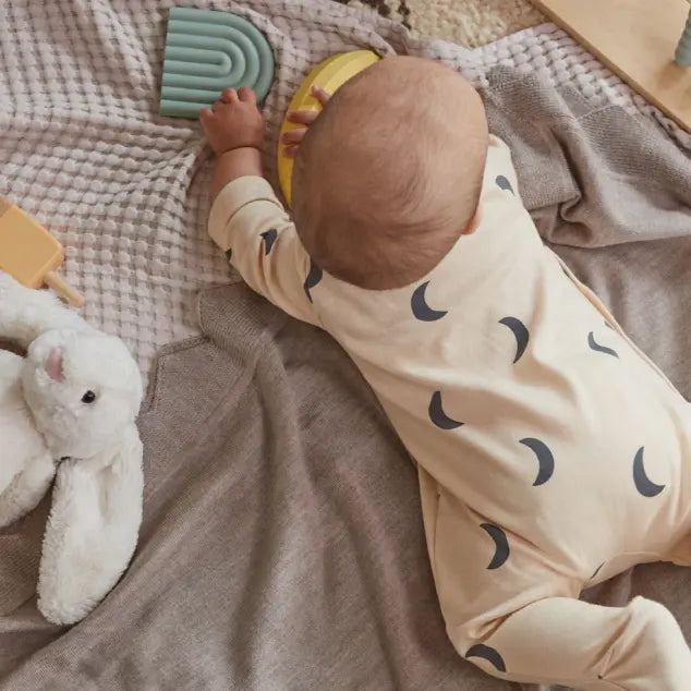 nourrisson qui n'est pas emmailloté, qui joue avec des jouets par terre