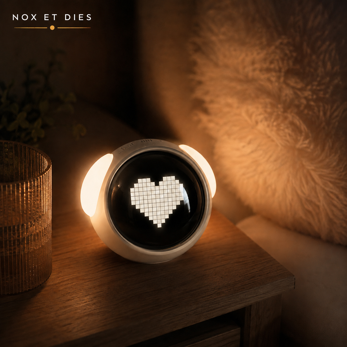 Réveil veilleuse Mimi Nox et Dies coloris blanc affichant une expression cœur, posé sur une table de chevet, lumière chaude allumée le soir