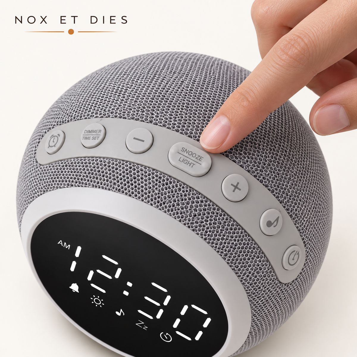 Réveil veilleuse Nox et Dies en tissu gris, gros plan sur les boutons de réglage (alarme, luminosité, snooze, volume) avec main actionnant la commande.