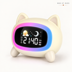 Réveil veilleuse enfant Wouaf Nox et Dies vu de trois-quarts, oreilles de chien dressées et pattes crème, halo lumineux allumé autour de l'écran LED